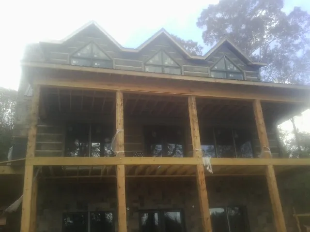 Dormers and porch framing on a large log home under construction — Roof Coating work by our crew in Judsonia
