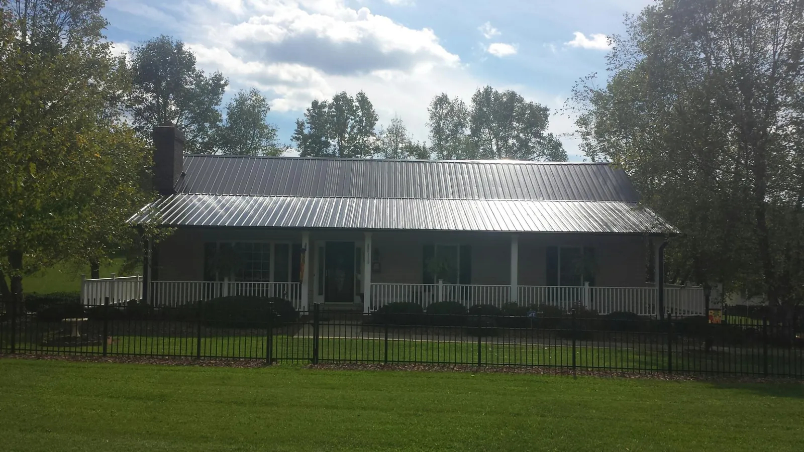 Gray metal roof on a brick ranch with a full width front porch — Gutter Guard Installation work by our crew in Judsonia