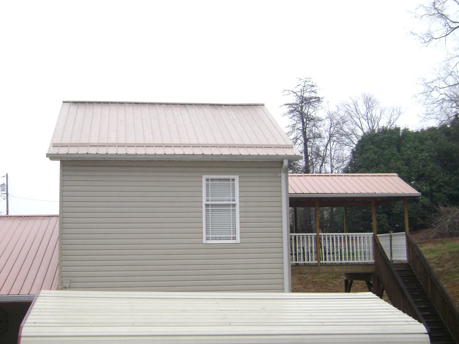 Tan metal roofs on a two story addition and attached porch, from a Roof Replacement job in Judsonia