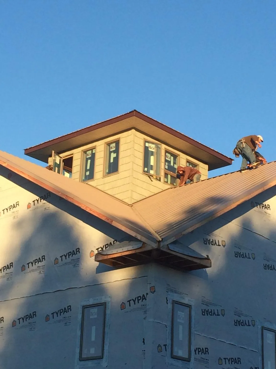 Roofers working around a rooftop cupola on a new metal roof at sunset — Roof Waterproofing in Judsonia by Roofing Brothers